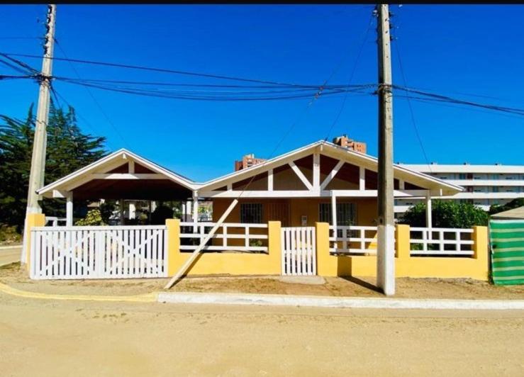 une maison jaune avec une clôture blanche devant elle dans l'établissement El tabo house, à El Tabo