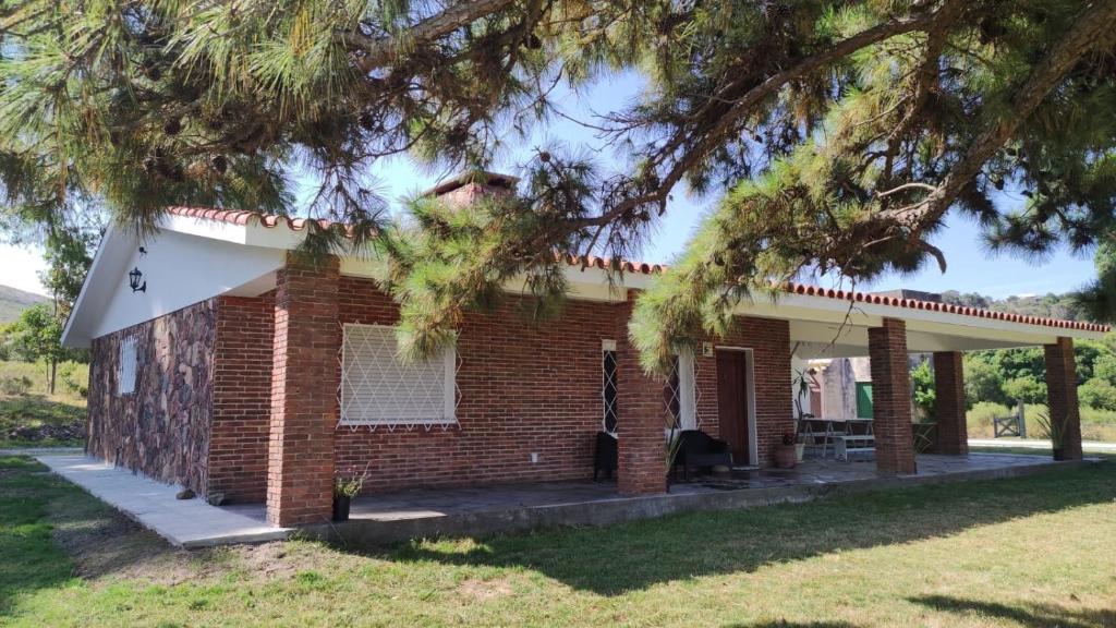 a brick house with a tree in front of it at Chalet de campo in Piriápolis
