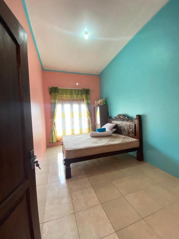 a bedroom with a bed in a room with a window at Homestay loteng in Madasari