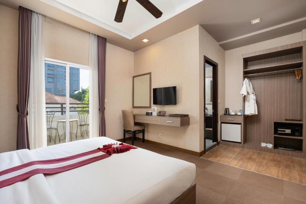 una camera da letto con un letto e una scrivania con una televisione di Clover Hotel a Phumĭ Prêk Chrey