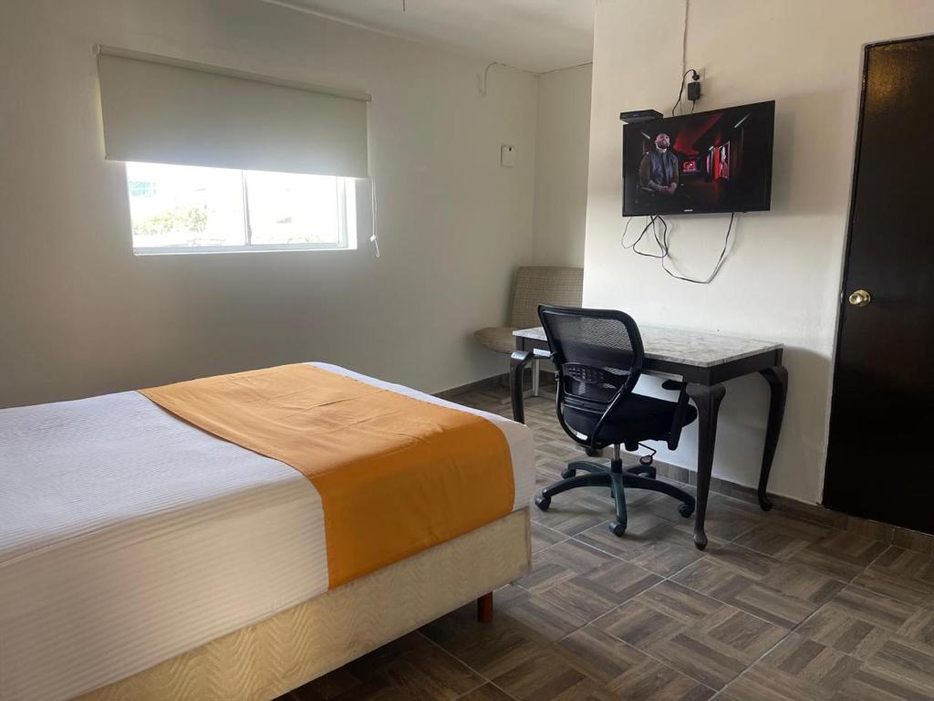 a bedroom with a bed and a desk with a computer at Hotel La Sexta in Tijuana