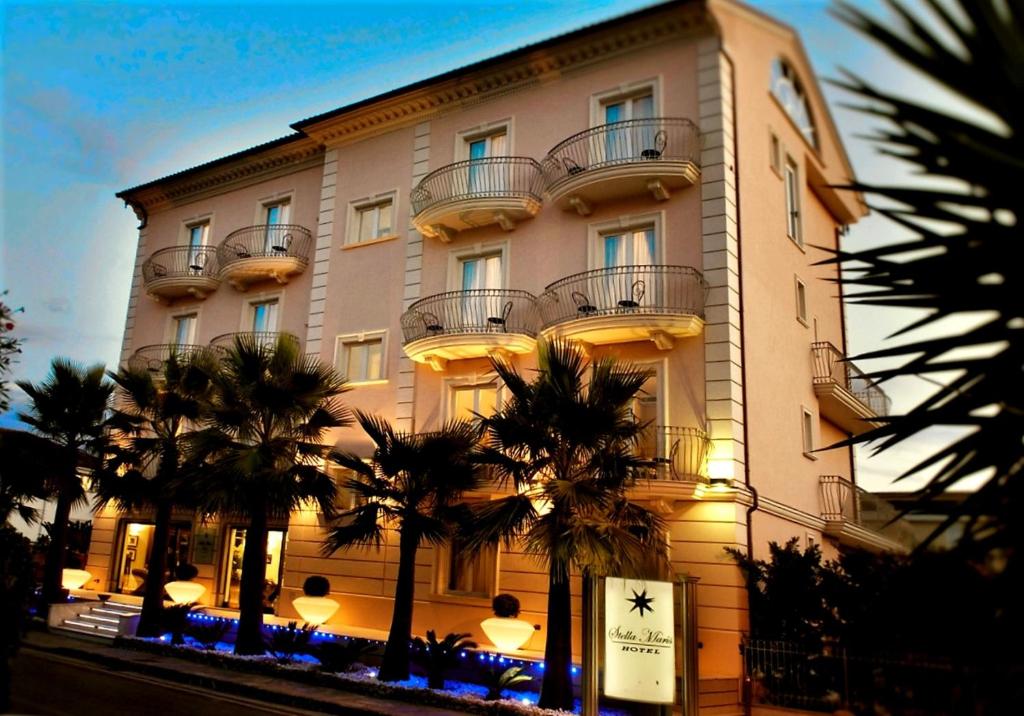 um grande edifício com palmeiras em frente em Hotel Stella Maris em Casal Velino