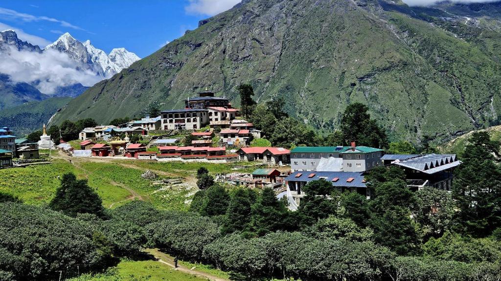 een groep gebouwen op een heuvel voor een berg bij The Himalayan Tyangboche in Lukla