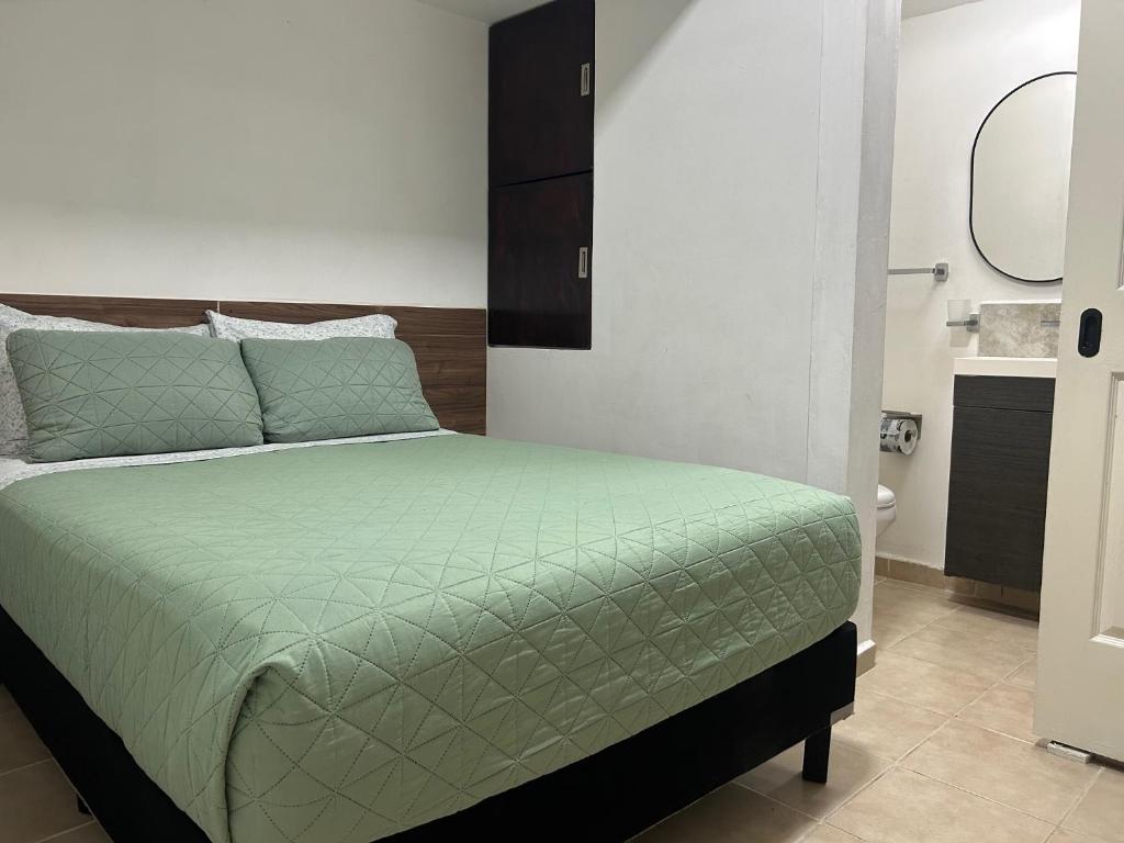 een slaapkamer met een bed met een groen dekbed bij Pequeño Alojamiento in Cancun