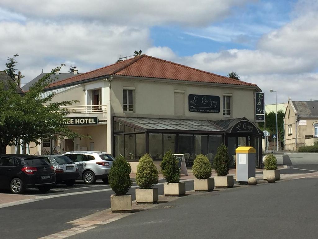 a building with cars parked in a parking lot at Hôtel Le Cerizay in Cerizay