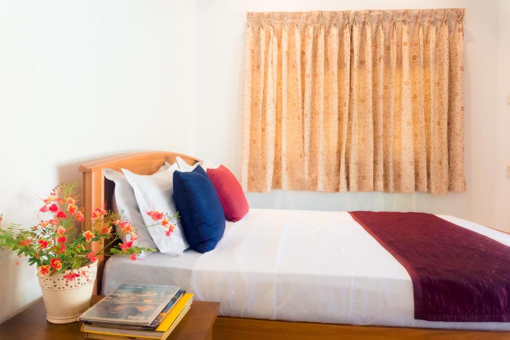 a bedroom with a bed with colorful pillows and a window at Abalone Stay in Bentota