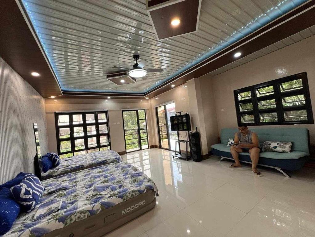 a woman sitting on a couch in a bedroom at Casa Ginhawa Ozamiz in Ozamis