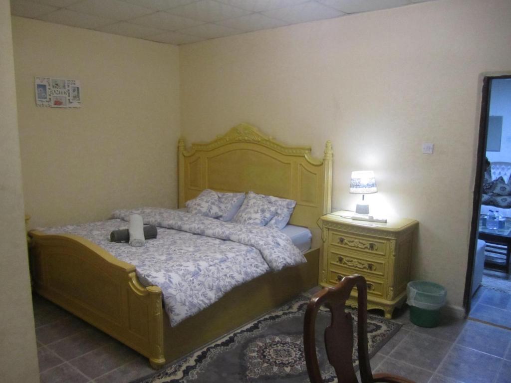 - une chambre avec un lit, une commode et une lampe dans l'établissement العين الهيلي مصباح ب1, à Al-Aïn