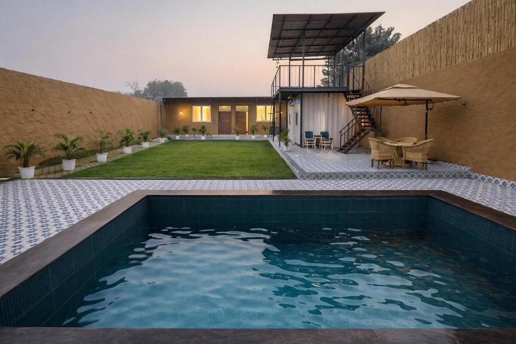 a swimming pool in the backyard of a house at Mud Meadows - Peace and Tranquility 3br Farm in Faridabad