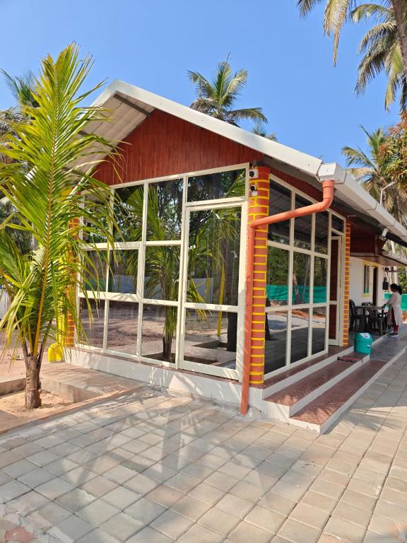 a house with large windows and a palm tree at His Grace BEACH AVENUE, Malpe Beach in Udupi