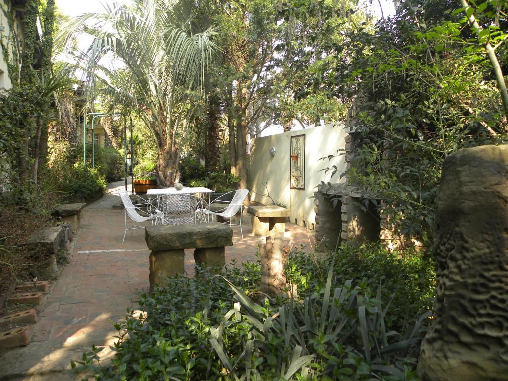 um pátio com uma mesa e cadeiras num jardim em Ladybrand Guest House em Ladybrand