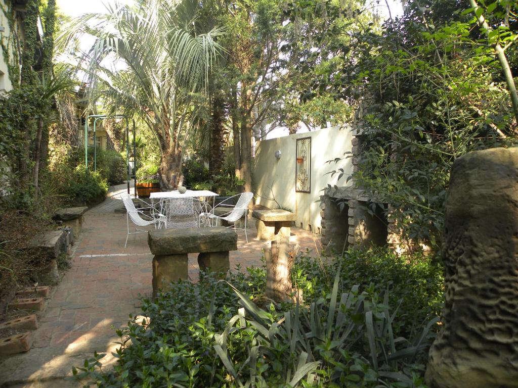 a patio with a table and chairs in a garden at Ladybrand Guest House in Ladybrand