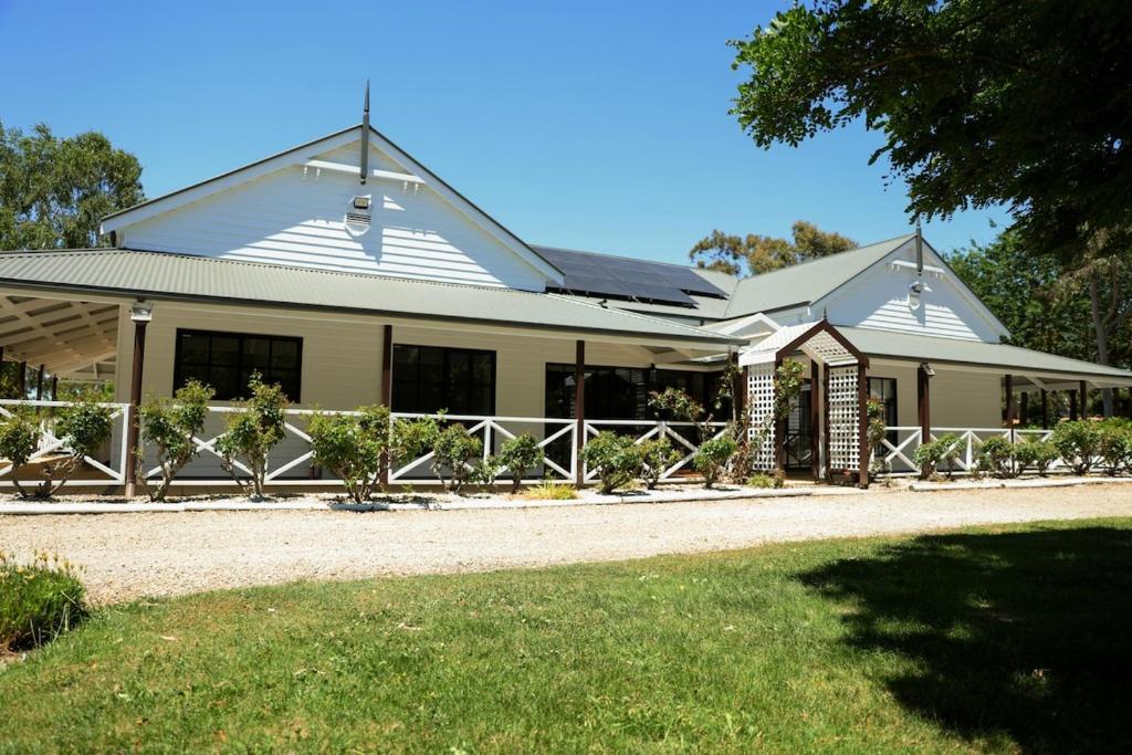 een wit huis met een hek ervoor bij Three Brothers Orchard in Oakbank