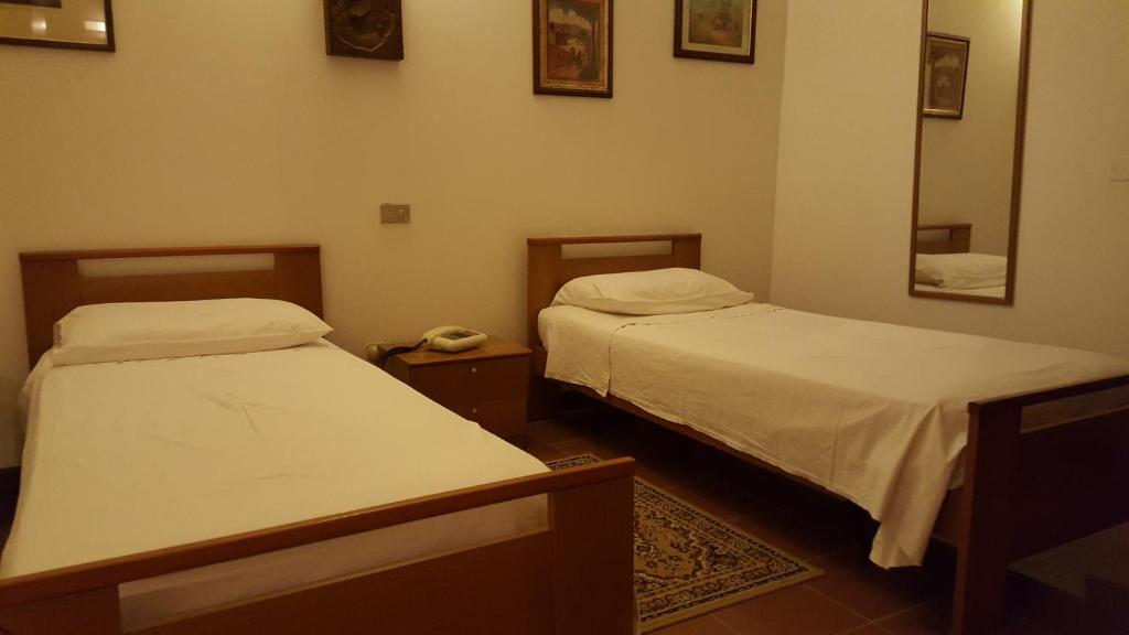 een kamer met 2 bedden en een spiegel bij Albergo Ristorante La Campagnola in San Salvaro
