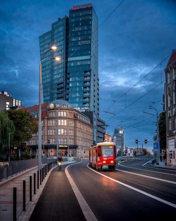 a red bus driving down a city street with tall buildings at Hanza Tower Level XV Signature in Szczecin