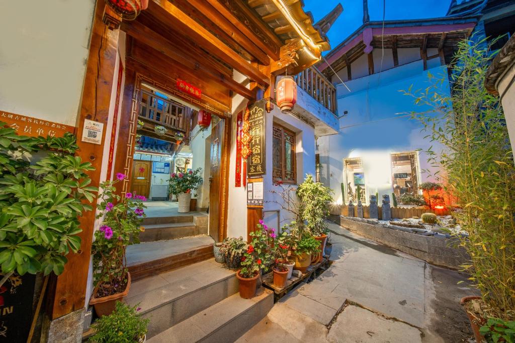 an old building with potted plants in a street at Travel & Rest Inn in Lijiang
