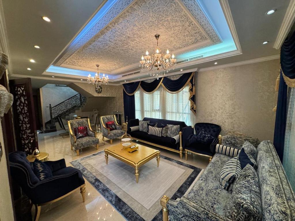 een woonkamer met blauwe meubels en een kroonluchter bij Luxury Villa Mansion Ajman in Ajman 