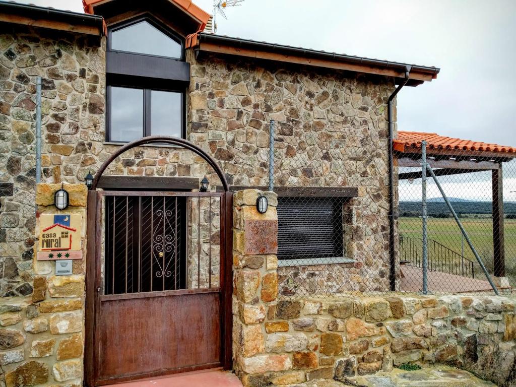 a stone house with a wooden door and a fence at La Casona del Silencio in Canos