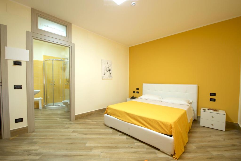 a yellow bedroom with a bed and a bathroom at Relais Piazza Garibaldi in Terracina