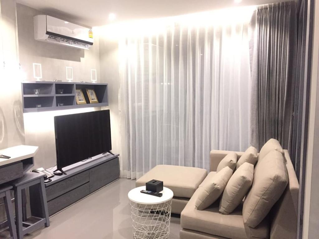 een woonkamer met een bank en een flatscreen-tv bij luxury apartment at Kamala in Kamala Beach