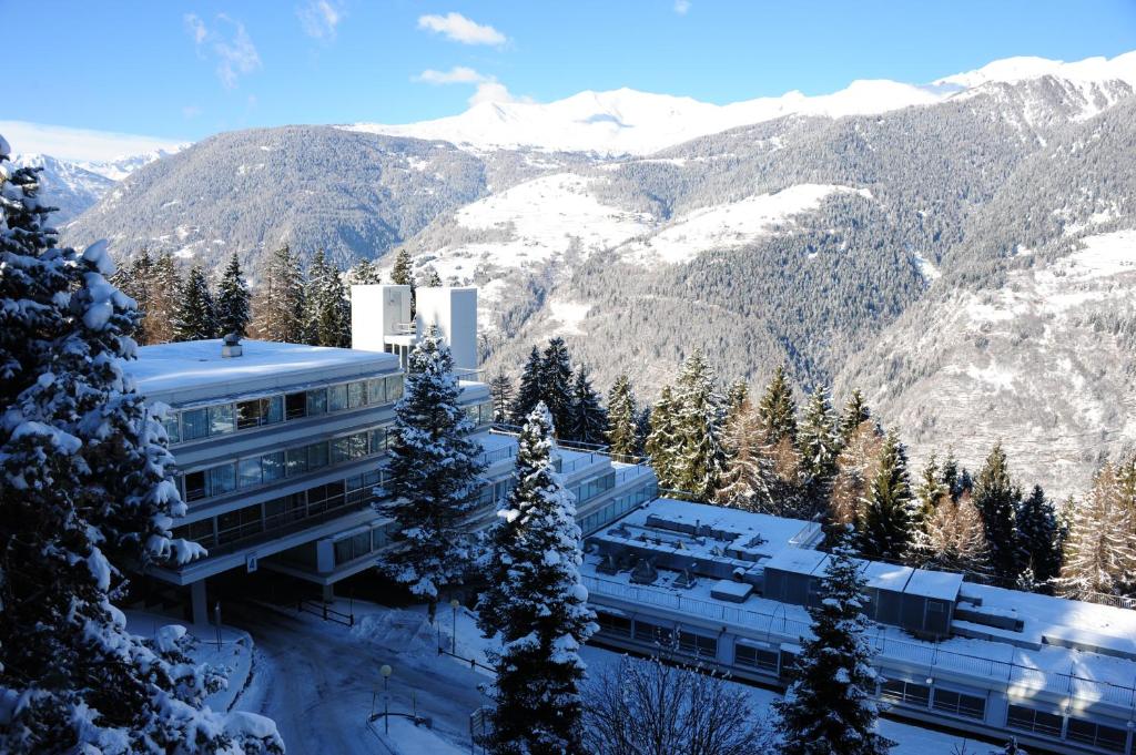 a building in the snow with mountains in the background at Residenza Albaré in Marilleva