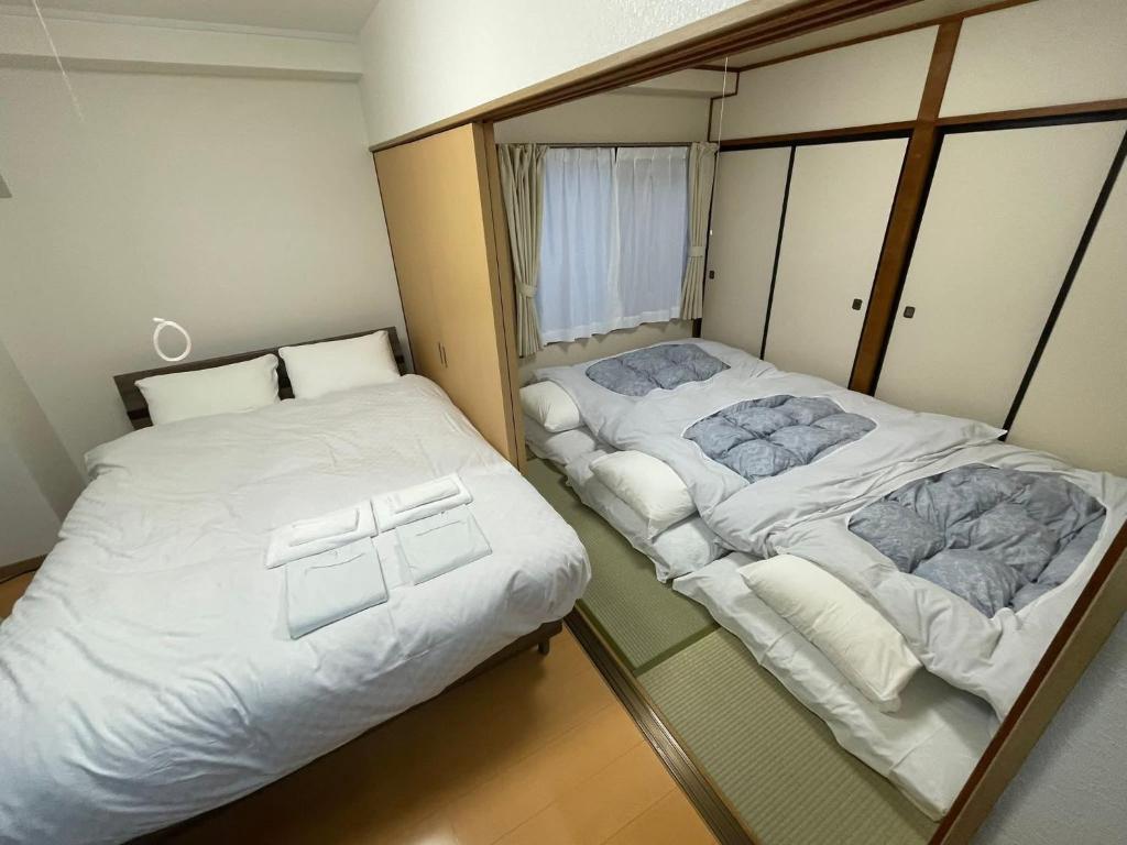 twee bedden in een kleine kamer naast elkaar bij サムライ シティ イン 信夫屋 in Aizuwakamatsu