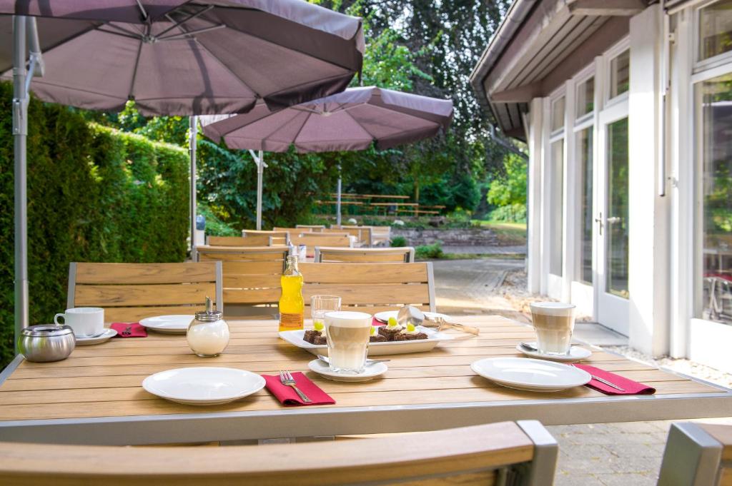 a wooden table with plates of food and an umbrella at CJD Bonn Castell in Bonn