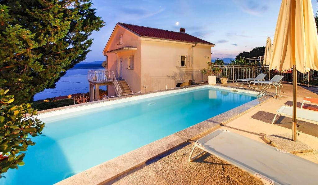 een zwembad met een parasol en een huis bij Holiday Home Marija with Pool & Garden & Amazing Sea View in Dramalj