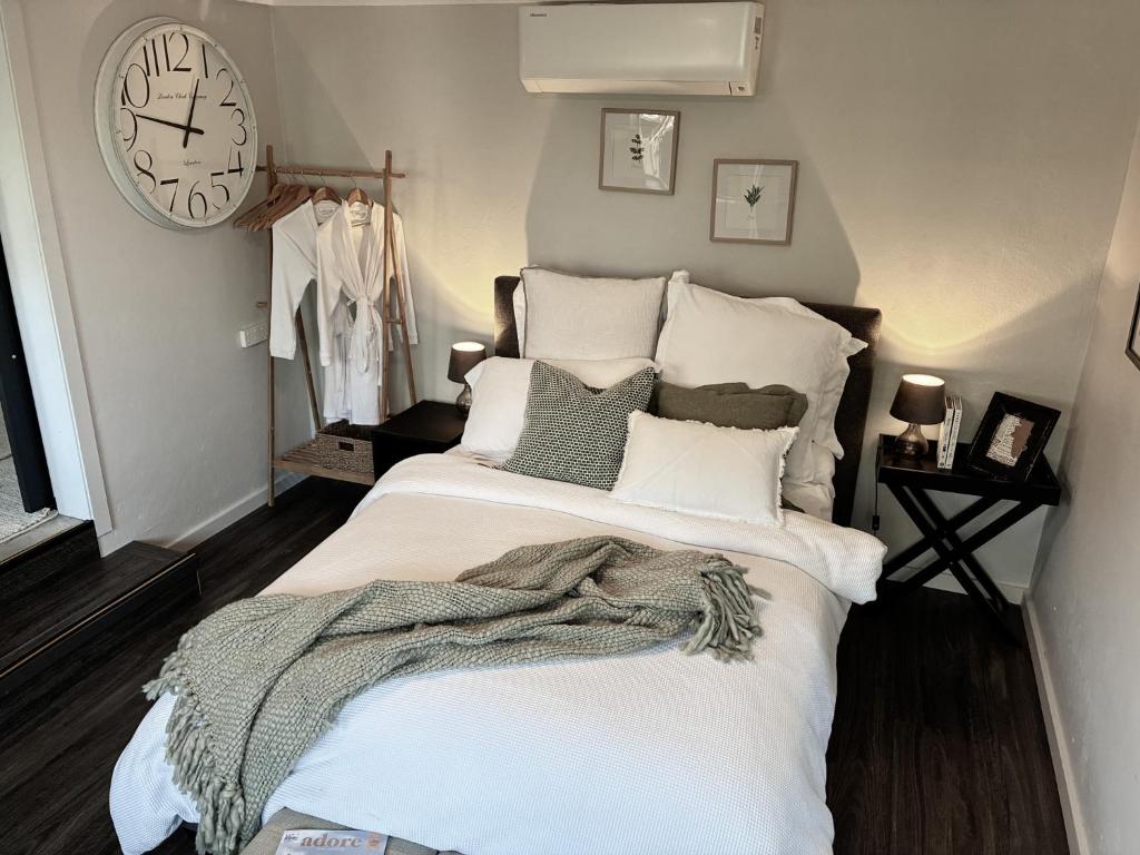 a bedroom with a bed with a clock on the wall at Courtyard Pool Studio Private Luxe Retreat in Coal Point