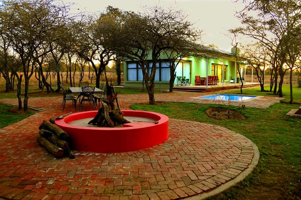 einen Brunnen in der Mitte eines Gartens mit einem Haus in der Unterkunft Crimson Bush Lodge in Klipdrift