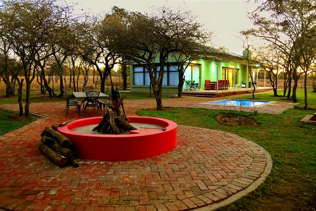 a fountain in the middle of a yard with a house at Crimson Bush Lodge in Klipdrift