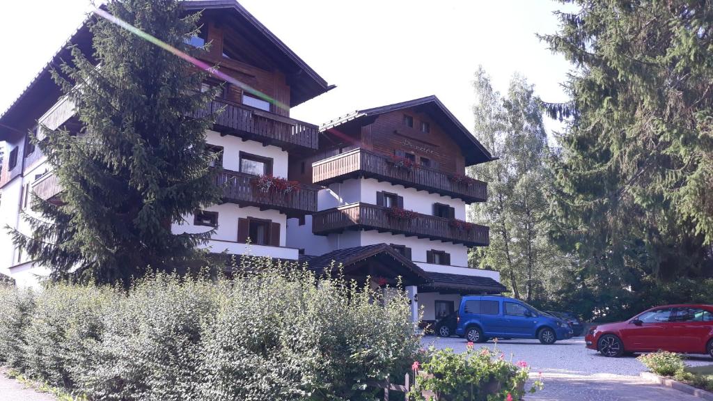 a building with balconies and cars parked in a parking lot at Hotel Principe in Cortina dʼAmpezzo
