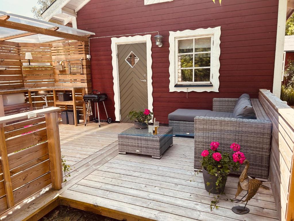 a patio with a couch and flowers in front of a house at Kaj's Cabin in Listerby