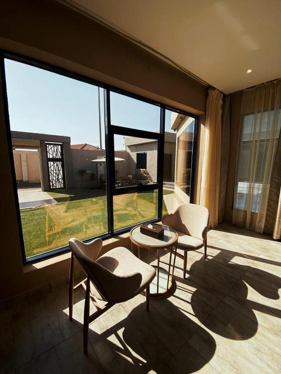 a room with two chairs and a table and large windows at شاليهات ايفا 2 in Taif