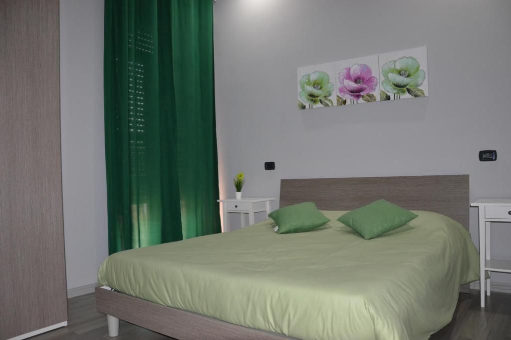 ein Schlafzimmer mit einem Bett mit grünen Vorhängen und Blumen in der Unterkunft Iris Inn in Salerno