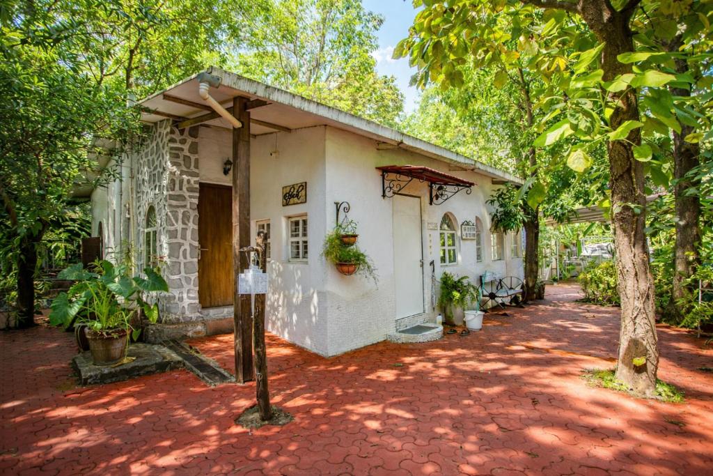 ein kleines weißes Gebäude mit Bäumen davor in der Unterkunft Elfreda, Vikramgad - 1BHK Villa - Pet Friendly in Zadapoli