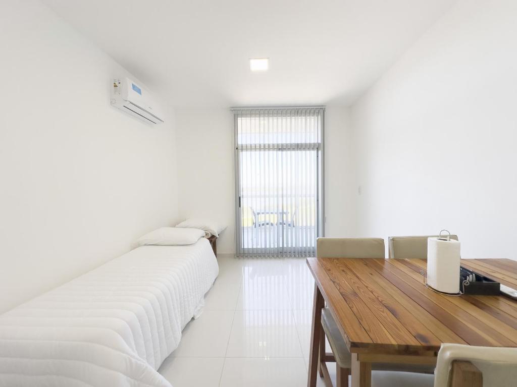 ein weißer Raum mit einem Holztisch und einem Bett in der Unterkunft Moderno con vistas al Río in Pueblo Esther