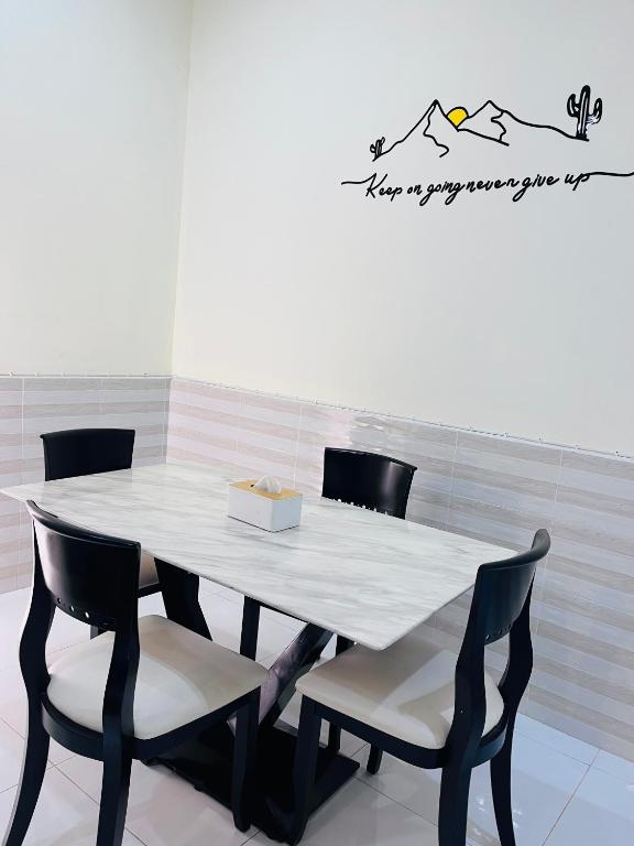 a dining room table with chairs and a white table at Farwa home in Kampong Rusamileh