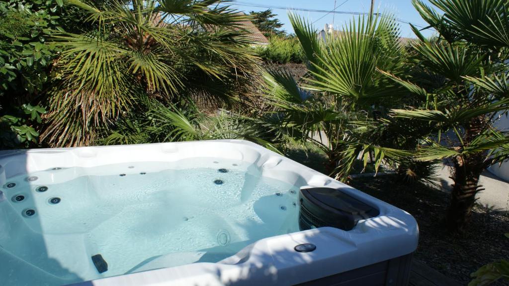 einen Whirlpool in einem Garten mit Palmen in der Unterkunft Maison 3 chambres avec Jacuzzi à 400m des plages in La Plaine-sur-Mer