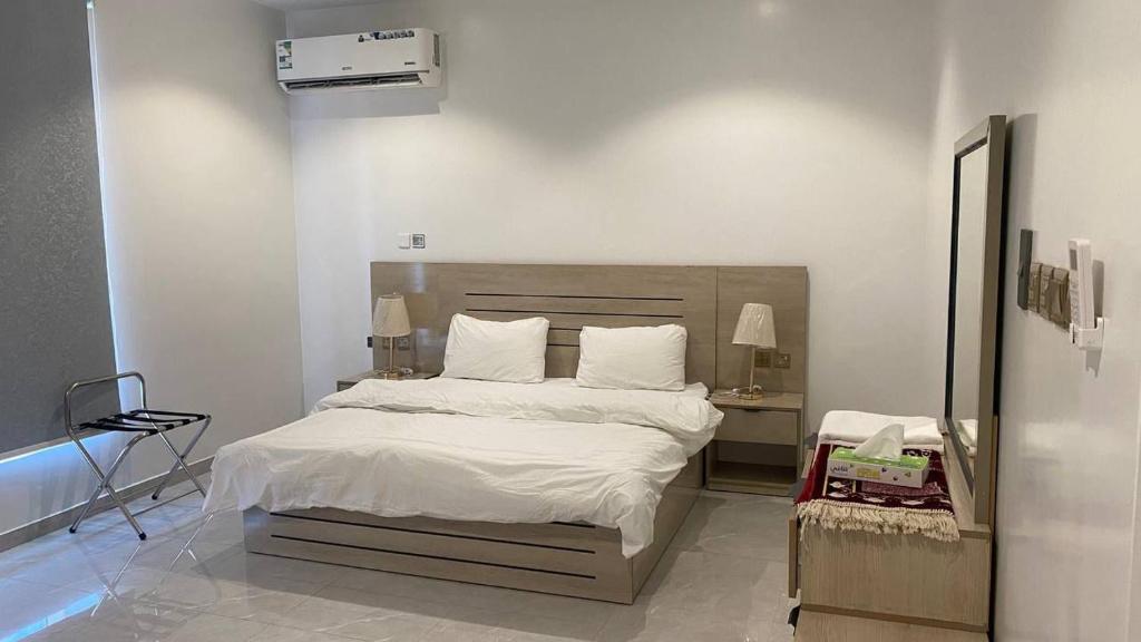 een slaapkamer met een groot bed met witte lakens en kussens bij نسيم الربيع 2 للشقق المخدومة in Quai