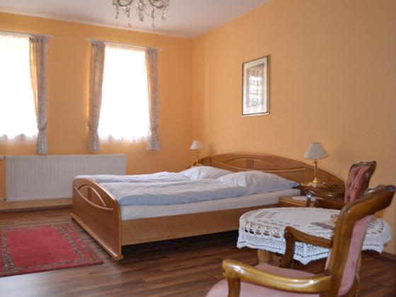ein Schlafzimmer mit einem Bett, einem Tisch und einem Stuhl in der Unterkunft Apartmenthaus im Augustinern in Quedlinburg