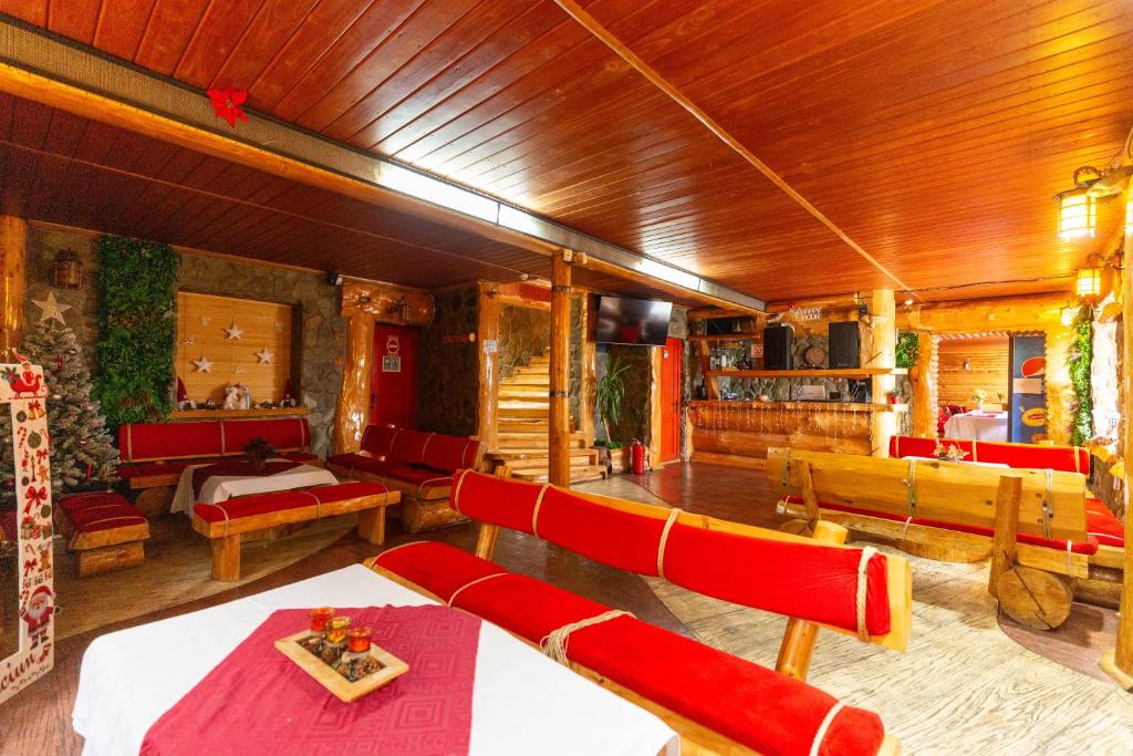 ein Wohnzimmer mit roten Stühlen und Tischen und ein Zimmer mit in der Unterkunft Pensiunea Alpin SPA in Ranca