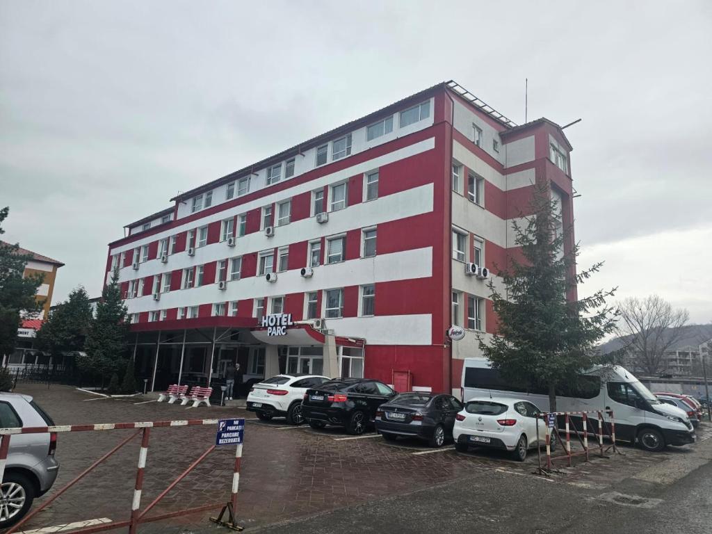 un edificio rosso e bianco con auto parcheggiate in un parcheggio di Hotel Parc a Onești