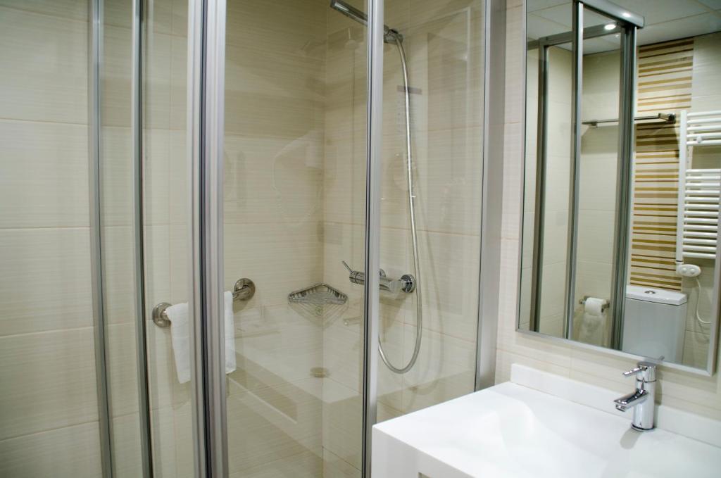a white bathroom with a shower and a sink at Hotel Porto Calpe in Calpe