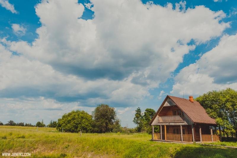 une vieille maison dans un champ avec un ciel nuageux dans l'établissement Pirts Rudzupuķes, à Svente