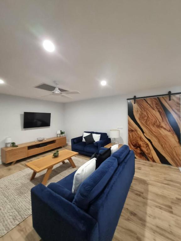 a living room with two blue couches and a table at Sheik Oasis in Lightning Ridge
