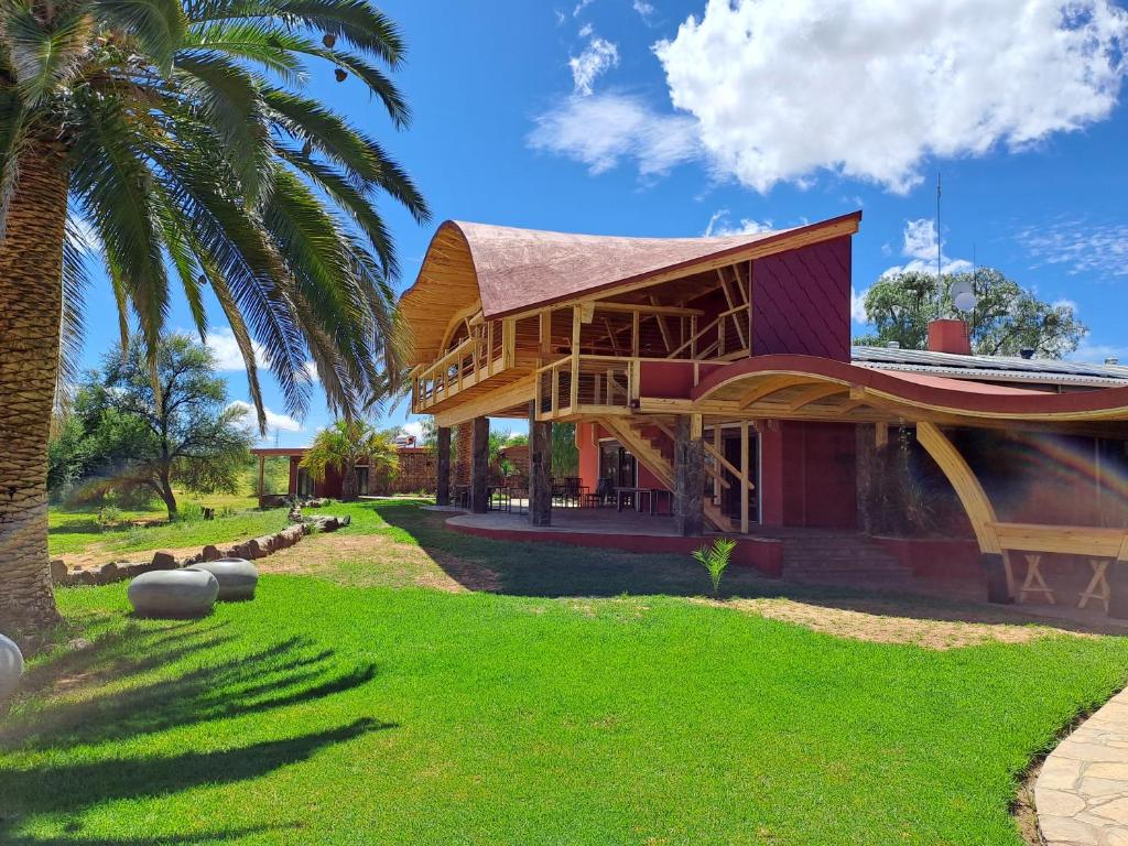 a house with a straw roof and a palm tree at Auas Safari Lodge in Windhoek