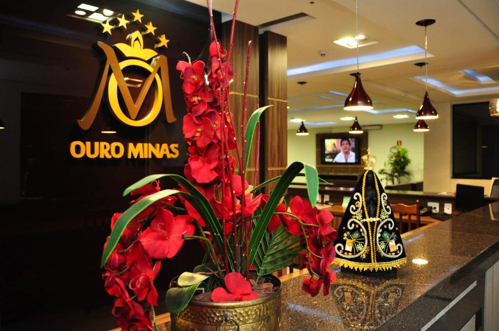 a restaurant with a counter with red flowers on it at Ouro Minas Plaza Hotel in Aparecida