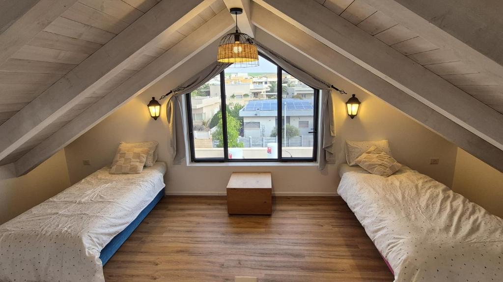 two beds in a room with a window at קיבוץ שדה נחום Green House in Sede Naẖum
