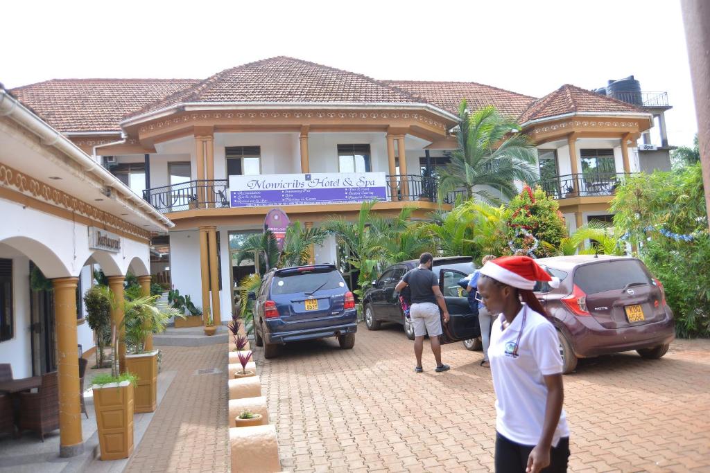 een vrouw met een kerstmuts loopt voor een gebouw bij Mowicribs Hotel and Spa in Entebbe